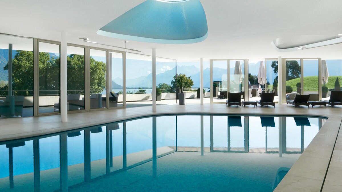 Clinique La Prairie indoor spa pool with panoramic Lake Geneva and Swiss Alps views through floor-to-ceiling windows
