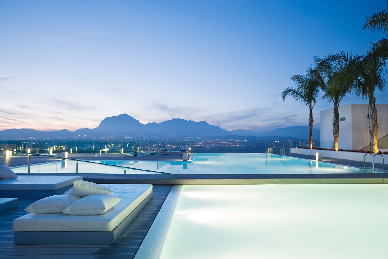 SHA Wellness Clinic infinity pool at dusk — illuminated pool with Alicante city lights and mountains