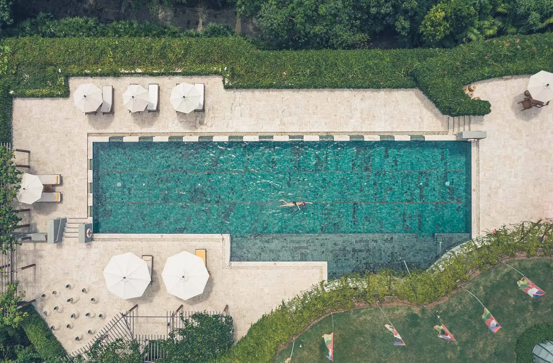 Aerial view of the 25-metre lap pool at Kamalaya Koh Samui surrounded by lush tropical gardens and sun loungers