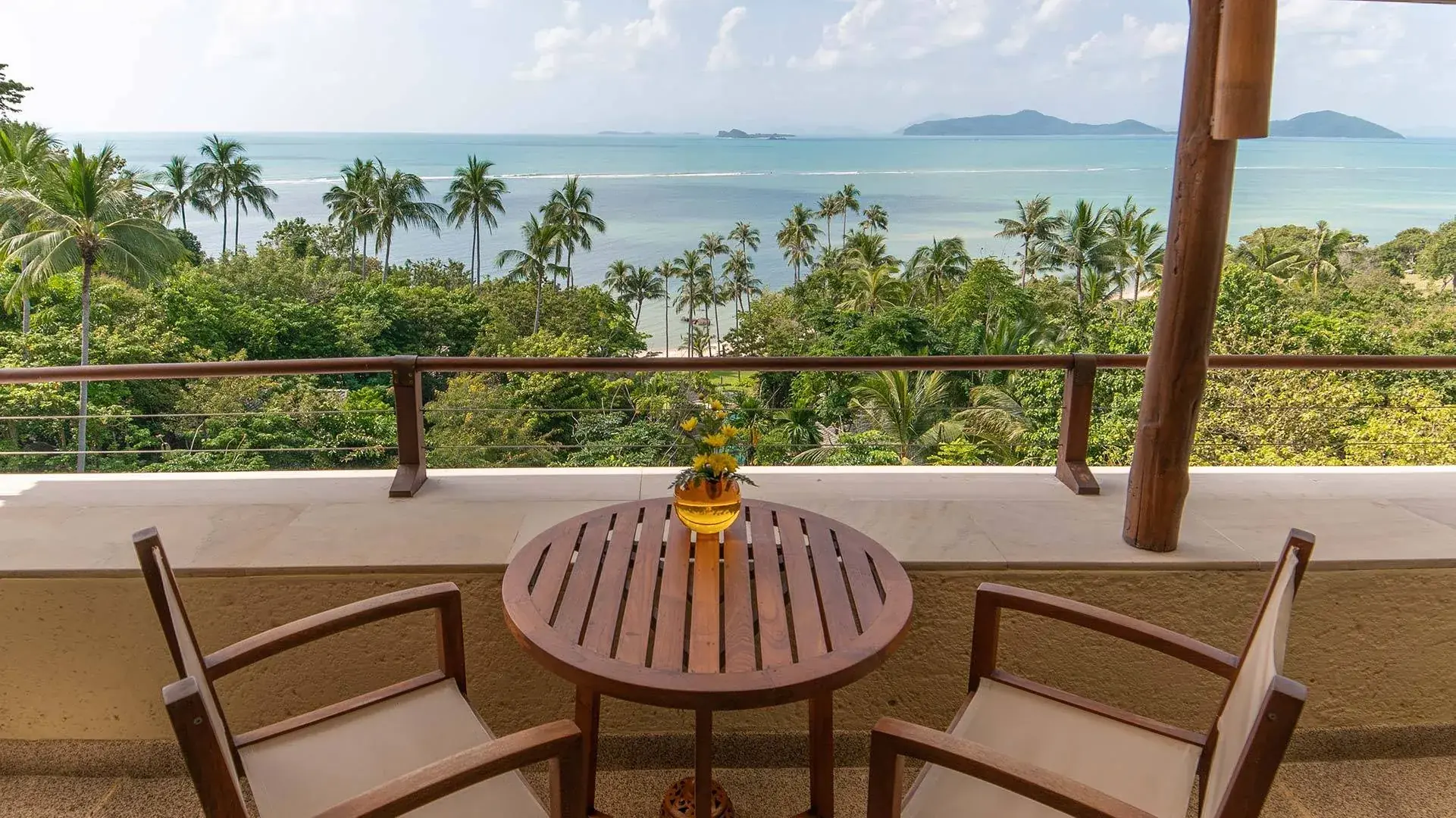 Private balcony of a luxury sea view suite at Kamalaya Koh Samui overlooking palm trees and turquoise Gulf of Thailand waters